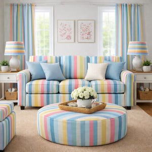 Könnte beinhalten: Ein Wohnzimmer-Set mit gestreiftem Sofa, Ottoman und Vorhängen in Pastellfarben. Das Sofa hat blaue Kissen und wird von passenden Lampen und Beistelltischen flankiert. Ein runder Ottoman steht vor dem Sofa.