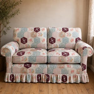 Peut inclure: Un canapé deux places recouvert d'un tissu patchwork à motif hexagonal répétitif. Le design présente des hexagones alternés bleu clair, crème et bordeaux foncé décorés de motifs floraux et de nœuds, avec une jupe à volants à la base.