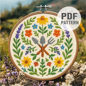 Könnte beinhalten: Ein runder Stickrahmen mit einem Stoffstück, das ein handgesticktes Motiv von Gartengeräten wie einer Schaufel und einer Gabel zeigt, umgeben von gelben, orangen und blauen Blumen mit grünen Blättern. Der Text lautet PDF PATTERN.