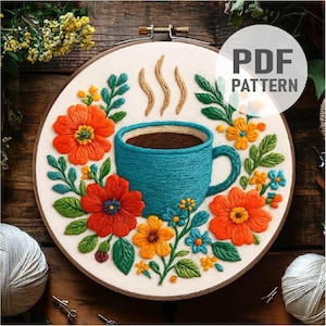Puede incluir: Bordado de una taza de café turquesa rodeada de flores naranjas, amarillas y azules sobre un aro de tela blanca. El texto "PDF PATTERN" está en un círculo blanco.