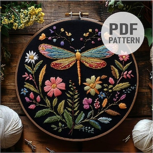Peut inclure: Un cerceau de broderie noir avec un motif de libellule et de fleurs colorées. La libellule est faite de fil à broder coloré et a un corps jaune, des ailes bleues et des accents rouges. Les fleurs sont roses, jaunes et violettes. La broderie est sur un fond de tissu noir.