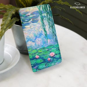May include: A rectangular phone case featuring a reproduction of Claude Monet's Water Lilies painting with vibrant blue, green, and pink brushstrokes. The design displays a pond surface with lily pads and hanging willow branches. Text reads GLITCHGLAMCO.