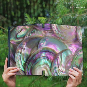 May include: A decorative panel with an iridescent abalone shell design. The panel features a black frame and a vibrant display of colors including pink, green, and purple. The text "GLITCHGLAMCO" is visible in the upper right corner.