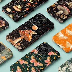 Puede incluir: Una colección de fundas para teléfonos con varios diseños. Las fundas presentan ilustraciones de setas, mariposas, ranas y estampados florales. La paleta de colores incluye negro, naranja, verde y diseños florales. Las fundas están dispuestas sobre una superficie azul claro.