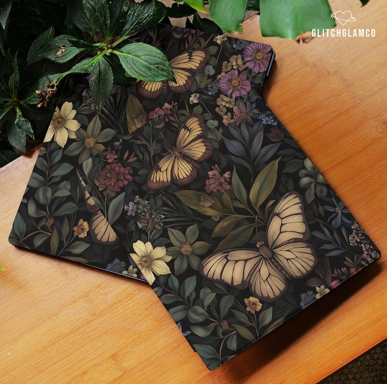 May include: Two rectangular decorative mats with a dark background featuring a floral and butterfly design. The butterflies are cream and brown, and the flowers are yellow, purple, and burgundy. The mats are on a wooden surface.