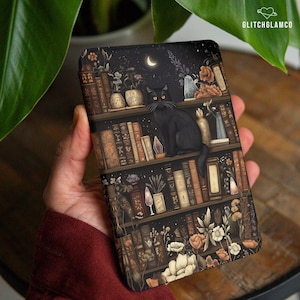 Puede incluir: Una funda de teléfono con una ilustración detallada de un gato negro posado en una estantería bajo un cielo nocturno con una luna creciente. La estantería está llena de libros, flores y velas. El texto "GLITCHGLAMCO" es visible en la esquina superior derecha.