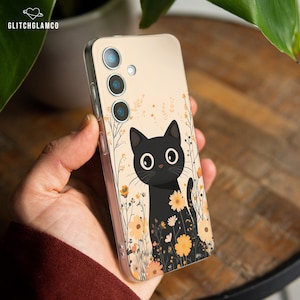 Könnte beinhalten: Handyhülle mit einer Illustration einer schwarzen Katze, umgeben von gelben und orangen Blumen und Blättern. Die Hülle hat einen beigen Hintergrund und einen transparenten Rand. Der Markenname "GLITCHGLAMCO" ist oben links zu sehen.