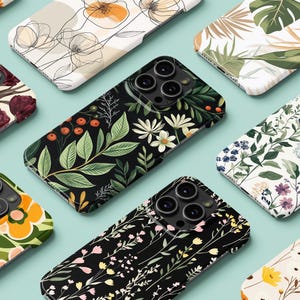 May include: A selection of phone cases showcasing floral and botanical patterns. The cases display designs such as tulips, daisies, and leaves, in shades of burgundy, green, and yellow. The cases are arranged on a light blue surface.
