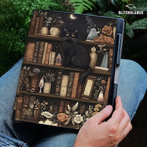 Può includere: Una custodia nera per laptop con un'illustrazione fantasy di un gatto nero su una libreria. Gli scaffali sono pieni di libri, piante e oggetti decorativi. Una luna crescente e stelle sono sullo sfondo, con il testo "GLITCHGLAMCO".
