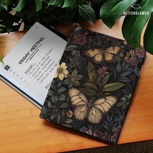 May include: A digital tablet with a floral butterfly design cover rests on a wooden surface next to an open tablet displaying a meeting agenda. The cover features butterflies and flowers in shades of beige, brown, and purple against a dark background.