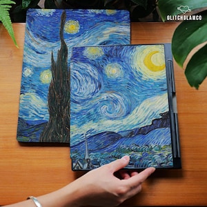 Puede incluir: Dos artículos con una impresión de "La noche estrellada" de Van Gogh. Uno es una funda rectangular para tableta, y el otro es un artículo rectangular con un marco negro. Están sobre una superficie de madera. El texto "GLITCHGLAMCO" está en la esquina superior derecha.