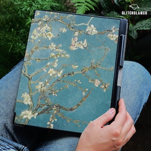 Puede incluir: Una funda para tableta con una impresión de la pintura "Almendros en flor" de Vincent van Gogh. La funda tiene un fondo verde azulado con flores blancas y rosas sobre ramas marrones. El texto "GLITCHGLAMCO" es visible.