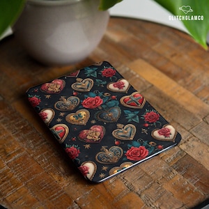 Könnte beinhalten: Eine schwarze rechteckige Hülle mit einem sich wiederholenden Muster aus verzierten Herzen und roten Rosen. Die Herzen haben verschiedene Designs, darunter Kreuze, Rosen und Totenkopfmotive. Die Hülle hat einen metallischen Rand und den Text "GLITCHGLAMCO".