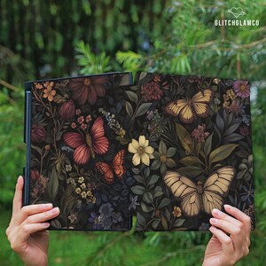 May include: Two open, dark-colored panels with a floral and butterfly design. The panels feature a variety of flowers in shades of red, yellow, and purple, along with several butterflies. The text "GLITCHGLAMCO" is in the upper right corner.