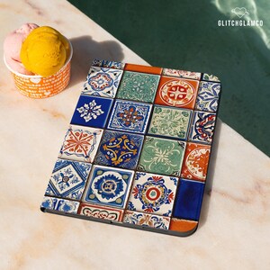 May include: A tablet case with a colorful tile design. The case features a pattern of square tiles in shades of blue, orange, green, and white. The design is reminiscent of traditional ceramic tiles.
