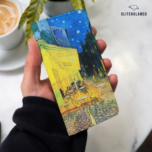 May include: A rectangular phone case featuring a printed reproduction of Vincent van Gogh's Cafe Terrace at Night painting. The design displays a bright yellow cafe terrace against a dark blue starry sky. The text GLITCHGLAMCO is printed in black.