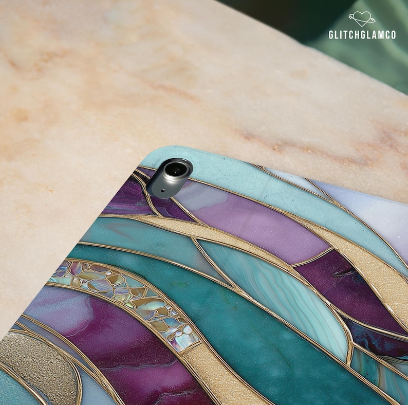 Pu&ograve; includere: Una custodia per iPad con un design a vetrata. La custodia presenta un motivo di forme curve nei toni del verde acqua, viola e oro. La custodia ha un obiettivo della fotocamera metallico e il testo "GLITCHGLAMCO" nell'angolo in alto a destra.