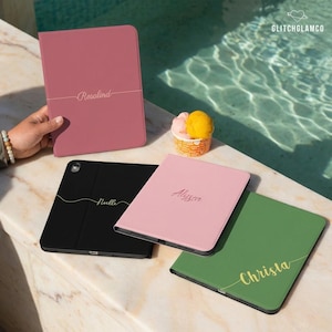 May include: A collection of personalized tablet cases in various colors, including pink, black, and green. Each case features a name in elegant script. The cases are displayed near a pool, with a small dessert cup in the background.