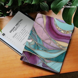 May include: A digital tablet with a colorful, abstract design in shades of purple, teal, and gold. The tablet is open, displaying a "Friday Meeting" agenda. The text "GlitchGlamco" is in the upper right corner.