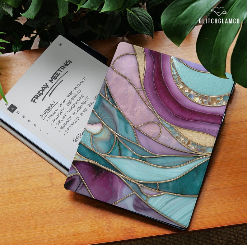 May include: A digital tablet with a colorful, abstract design in shades of purple, teal, and gold. The tablet is open, displaying a "Friday Meeting" agenda. The text "GlitchGlamco" is in the upper right corner.