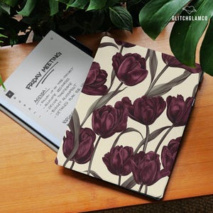 Può includere: Un tablet digitale con una cover color crema con un motivo di tulipani bordeaux scuro e foglie grigie. Il tablet è aperto, mostrando un ordine del giorno "FRIDAY MEETING" con note scritte a mano. Il marchio "GLITCHGLAMCO" è visibile.