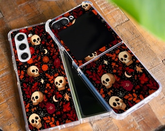 May include: Two clear phone cases with a black background, adorned with white skulls, red leaves, and floral patterns. The cases are open, revealing the phone's screen. The brand name "GLITCHGLAMCO" is visible.