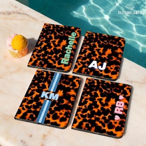Op de afbeelding: Vier gepersonaliseerde telefoonhoesjes met een schildpadpatroon. Eén hoesje heeft de naam "Rachelle" in groen, een ander de initialen "AJ" in wit, een derde "KM" met blauwe strepen en de laatste "RB" met een roze hart.