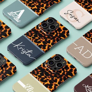 May include: A collection of personalized phone cases with a leopard print design. Each case features a unique name or initial in white script or block letters against a solid-colored background, including blue, beige, and brown.