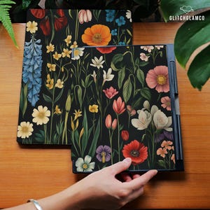 May include: Two black laptop covers with a vibrant floral design featuring red poppies, pink and white flowers, and bluebells. The covers are decorated with a variety of colorful flowers and green leaves.