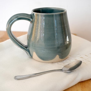 Eine handgedrehte Keramiktasse, glasiert in Eisblau mit gewelltem Rand
