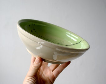 Handcrafted shallow stoneware bowl with green interior and black splatter design