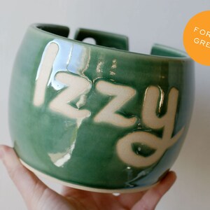 A glossy green knitting yarn bowl with the name 'Izzy'