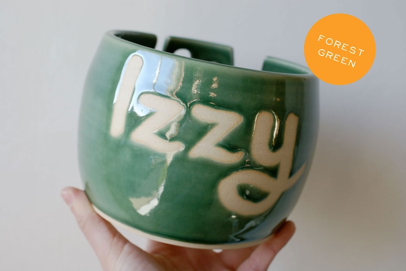 A glossy green knitting yarn bowl with the name 'Izzy'