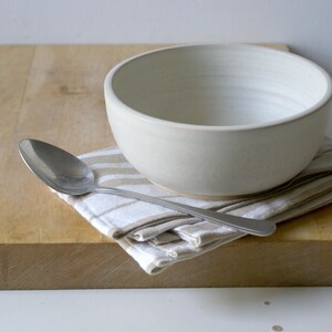 One large salad bowl glazed in vanilla cream with tablespoon for scale