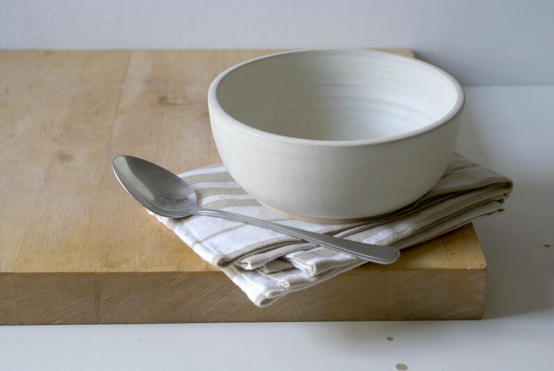 One large salad bowl glazed in vanilla cream with tablespoon for scale