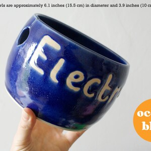 A dark blue ceramic yarn bowl with a custom name in the glaze