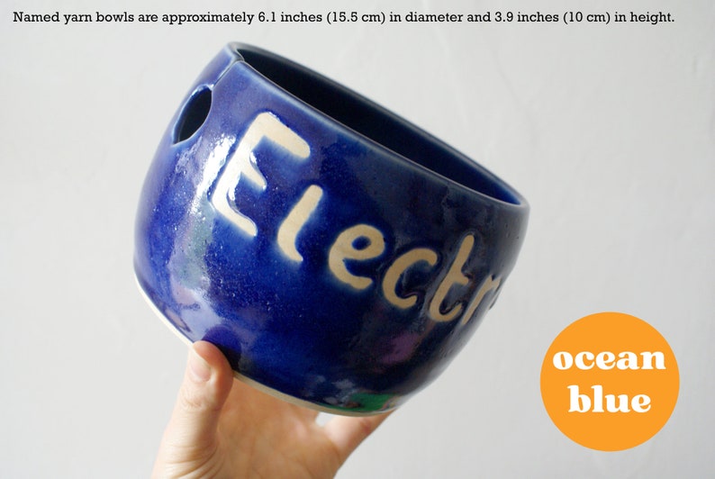 A dark blue ceramic yarn bowl with a custom name in the glaze