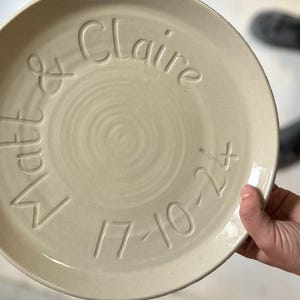 May include: A white ceramic plate with the words "Matt & Claire 17-10-21" inscribed on it.