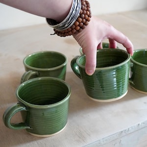 A hand thrown mug with a frog in the bottom glazed in glossy green