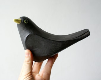 Handmade ceramic blackbird sculpture with a curious pose