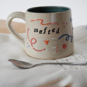 SALE - One hand thrown pottery mug with 'mafted' lettering and colourful slip trailing
