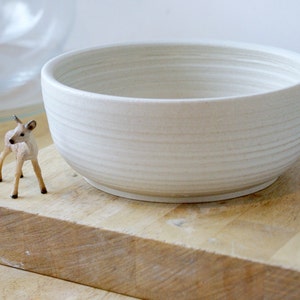 A stoneware pottery large salad bowl glazed in vanilla cream