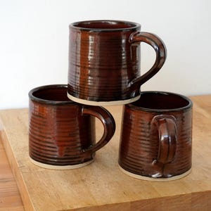 Taza de cerámica de gres torneada y esmaltada en rojo brillante.