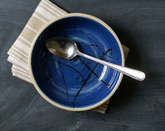 Hand thrown shallow stoneware bowl with blue interior and black splatter design