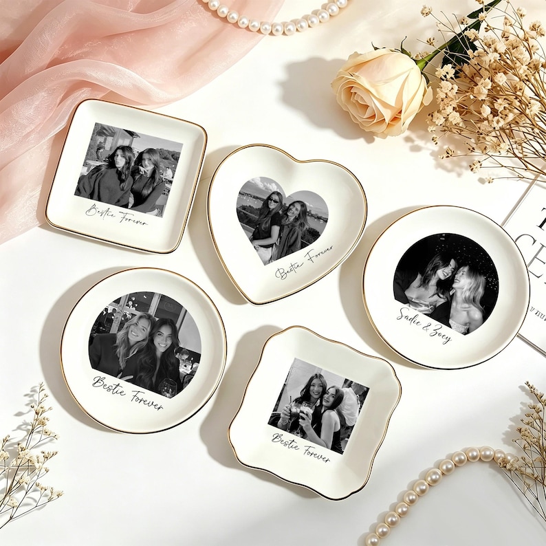 May include: Five white ceramic trinket dishes with gold-painted rims, each featuring a black and white photograph of two people. The dishes are square, heart-shaped, and round, with text printed below the photos reading Bestie Forever or Sadie & Zoey.