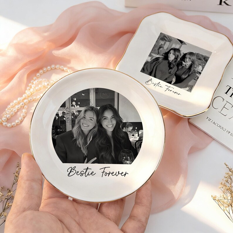 May include: Two white ceramic trinket dishes with gold-toned rims. One dish is round and the other is square with scalloped edges. Both feature a black and white photograph of two people and the cursive text "Bestie Forever" printed on them.