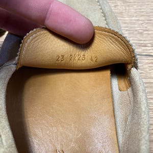 Op de afbeelding: Een beige su&egrave;de loafer met een lichtbruine leren voering. Op de binnenkant van de tong staan de cijfers 23 2223 42 gestempeld. De schoen heeft zichtbare stiksels langs de randen en een gladde binnenzool van lichtbruin leer.