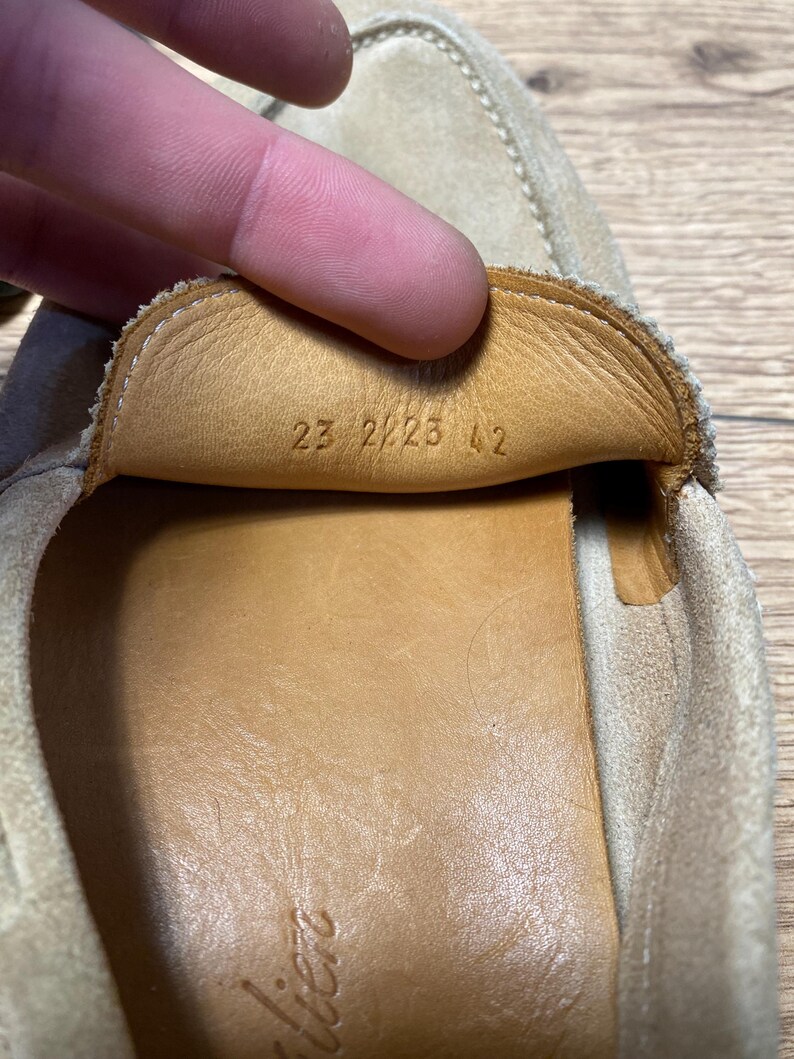 Op de afbeelding: Een beige su&egrave;de loafer met een lichtbruine leren voering. Op de binnenkant van de tong staan de cijfers 23 2223 42 gestempeld. De schoen heeft zichtbare stiksels langs de randen en een gladde binnenzool van lichtbruin leer.