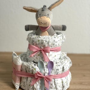 Torta di pannolini per bambina con peluche e cucchiaio per porridge. Perfetto per una nascita, un battesimo o un baby shower. A scelta anche personalizzato.