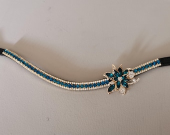May include: A blue and gold horse browband with a crystal flower design.